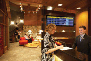 Young woman checking in at hotel reception desk, side view